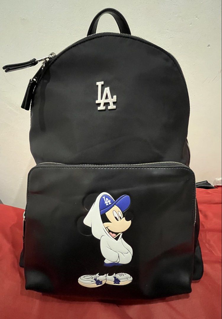MLB x Disney Mickey Mouse LA Dodgers Black Backpack (Category: Backpacks) located in Talisay. Submitted by cherylu (Listing ID 1466508607, Image 1). Description: MLB x Disney collaboration backpack in black nylon. Features Mickey Mouse graphic wearing an LA Dodgers hoodie and cap on the front pocket, plus silver LA logo hardware above. Zipper closure with MLB branding interior label and inner zip pocket. Protective plastic film still on zipper pu