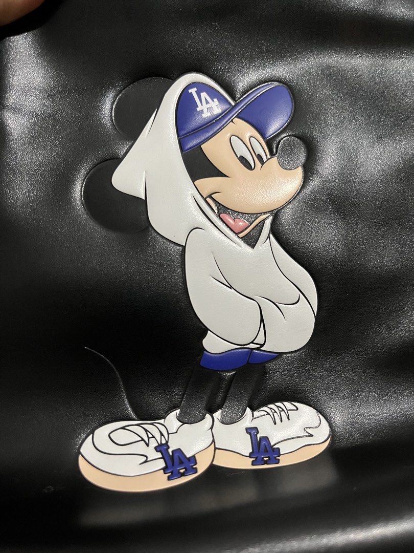 MLB x Disney Mickey Mouse LA Dodgers Black Backpack (Category: Backpacks) located in Talisay. Submitted by cherylu (Listing ID 1466508607, Image 2). Description: MLB x Disney collaboration backpack in black nylon. Features Mickey Mouse graphic wearing an LA Dodgers hoodie and cap on the front pocket, plus silver LA logo hardware above. Zipper closure with MLB branding interior label and inner zip pocket. Protective plastic film still on zipper pu