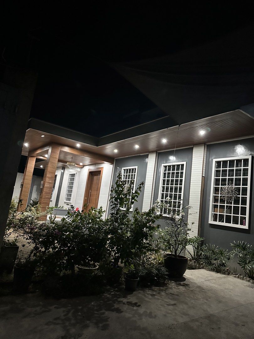 Modern 3 Storey House Interior and Exterior (Category: House & Lot) located in Angeles City. Submitted by rechell1969 (Listing ID 1466420413, Image 1). Description: Spacious 3- storey home with a neat outdoor porch setup and lush plants. Inside has a long open layout combining the living area and kitchen. Kitchen features a long marble-top island with wooden accents. Bedrooms have tiled floors, air conditioning, and plenty of room. Bathrooms have