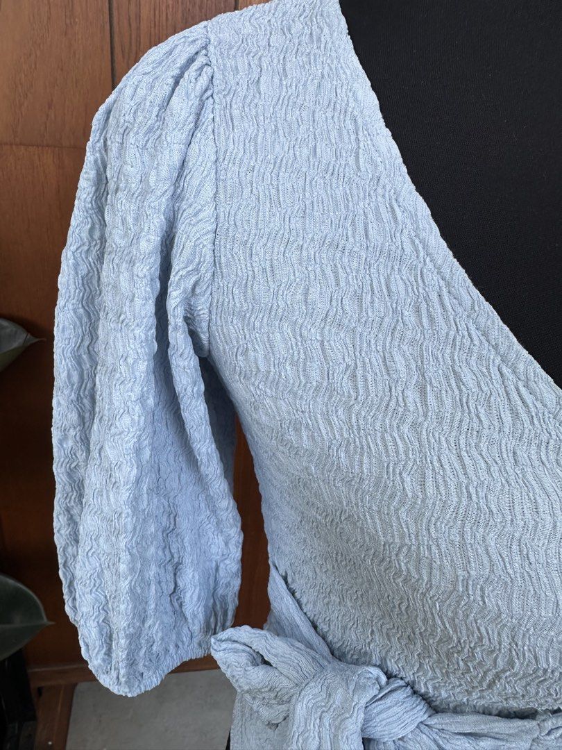 Monki Light Blue Wrap Blouse (Category: Blouses) located in Bulacan. Submitted by thriftbagcollections (Listing ID 1466360301, Image 2). Description: - Brand: Monki - Color: Light blue with textured crinkle fabric - Size: Tagged XS (fits small S as well) - Details: V-neckline, trendy puff sleeves, and adjustable side tie - Origin: Made in Turkey - Styling: Easy to pair with denim or skirts.