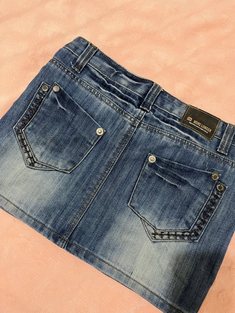 More Longer Denim Skirt (Category: Skirts) located in Las Pinas. Submitted by twister.sundae (Listing ID 1466372971, Image 2). Description: - Brand: More Longer - Style: Y2K vintage denim mini skirt, mid-wash blue - Details: Distressed whiskering effect on front and back - Pockets: Two back pockets with contrast decorative cross-stitching - Closure: Waist button closure with zip fly - Extras: Classic belt loops and metal button rivets (lost the m