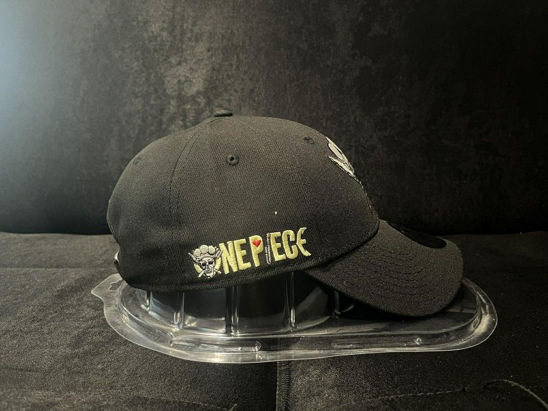 New Era 9FORTY One Piece Skull Chef Cap (Category: Caps & Hats) located in Manila. Submitted by monkeydelevi (Listing ID 1466424121, Image 2). Description: New Era 9FORTY adjustable cap. Black fabric featuring a One Piece chef skull logo embroidered on the front. Yellow One Piece lettering along the side. Knife embroidery detail on the back. Blue and white striped lining inside. Standard strapback closure with metal buckle. Original tag still att