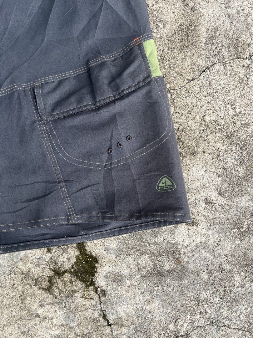 Nike ACG Cargo Boardshorts Grey Green (Category: Shorts) located in San Isidro, Leyte. Submitted by tigerxdx3580077 (Listing ID 1466414072, Image 3). Description: - Brand: Nike ACG - Waistline: 31to34 - Length: 22 - Color: Dark grey with muted green contrast panels - Features: Multiple utility pockets on the right leg with drainage grommets - Branding: Printed All Conditions Gear logo on the lower back leg - Closure: Button fly - Ideal for: Outdo