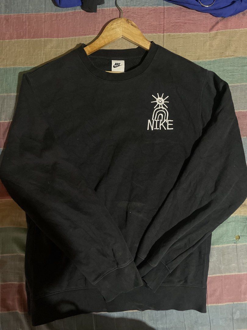 Nike Black Graphic Sweatshirt With Sun Design (Category: Coats, Jackets and Outerwear) located in Caloocan City. Submitted by ceejay0319 (Listing ID 1466420222, Image 1). Description: - Brand: Nike - Style: Crewneck sweatshirt - Color: Black - Design: Embroidered smiling sun and rainbow graphic with Nike text on the left chest - Material: Comfortable cotton blend - Fit: Standard fit - Condition: Excellent / Like new.