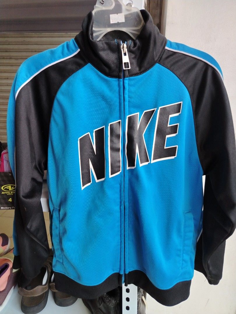 Nike Blue and Black Track Jacket Size 7 (Category: Babies & Kids Fashion) located in General Tinio. Submitted by crisantacruz (Listing ID 1466474749, Image 1). Description: - Brand: Nike - Color: Bright blue and black - Design: Big Nike lettering on front chest with white piping on shoulders - Features: Zip-up style, high neck collar, side pockets - Origin: Made in Indonesia - Size: Tagged size 7 - Condition: Excellent pre-loved condition.