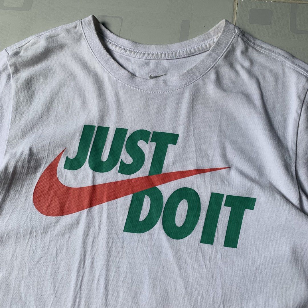 Nike Just Do It Graphic Tee White Size XS (Category: Activewear) located in Daraga. Submitted by vinteesfnds (Listing ID 1466393290, Image 2). Description: - Brand: Nike - NEED WASH - Color: White with green, red, and orange graphic - Design: Classic 'Just Do It' text over a large orange swoosh - Size: XS (tag printed inside the collar) - XS men , Medium Women - Material: 100% cotton - Fit: Regular fit, crew neck style - Condition: Excellent / Re