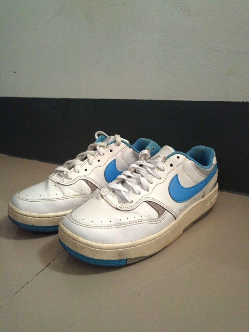 Nike White and Blue Low-Top Sneakers (Category: Sneakers) located in Mandaluyong City. Submitted by wildfalcon-b945 (Listing ID 1466436863, Image 3). Description: White leather sneakers with bright blue swooshes and matching blue inner lining. Classic low-top design with lace-up closure. Yellowed midsoles from previous wear. Soles show standard blue and grey tread pattern..