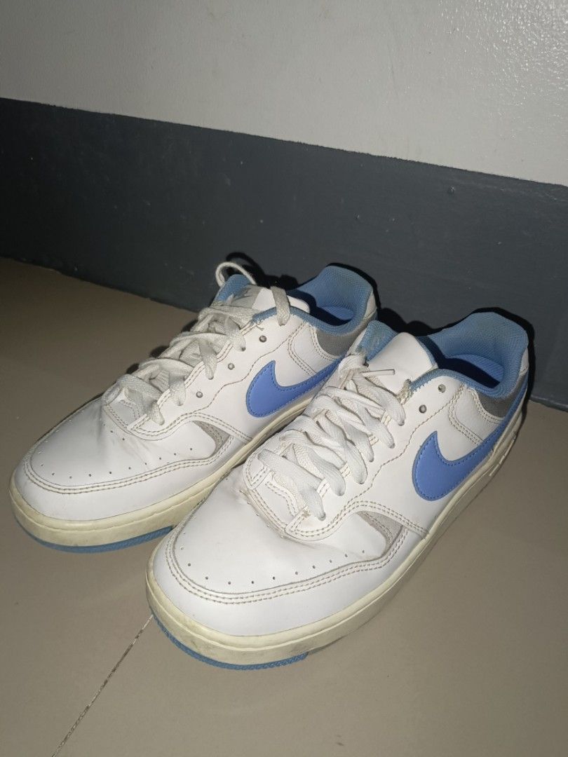 Nike White and Blue Low-Top Sneakers (Category: Sneakers) located in Mandaluyong City. Submitted by wildfalcon-b945 (Listing ID 1466436863, Image 1). Description: White leather sneakers with bright blue swooshes and matching blue inner lining. Classic low-top design with lace-up closure. Yellowed midsoles from previous wear. Soles show standard blue and grey tread pattern..