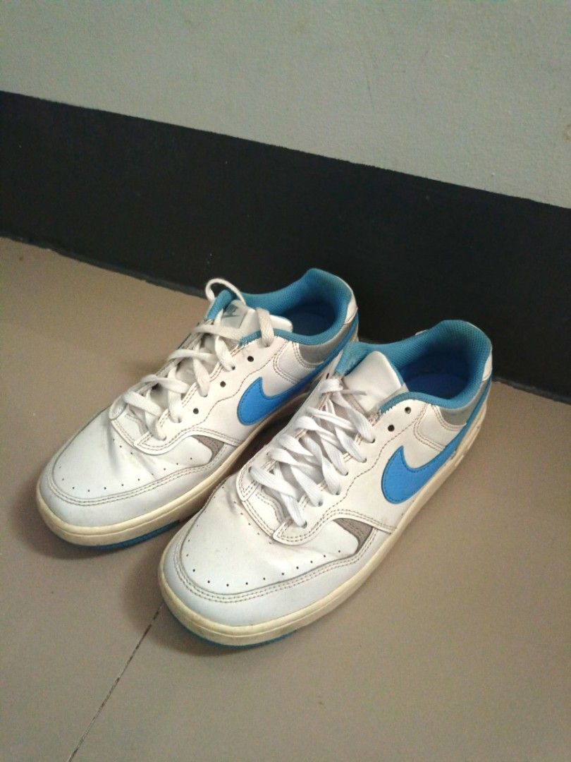 Nike White and Blue Low-Top Sneakers (Category: Sneakers) located in Mandaluyong City. Submitted by wildfalcon-b945 (Listing ID 1466436863, Image 2). Description: White leather sneakers with bright blue swooshes and matching blue inner lining. Classic low-top design with lace-up closure. Yellowed midsoles from previous wear. Soles show standard blue and grey tread pattern..