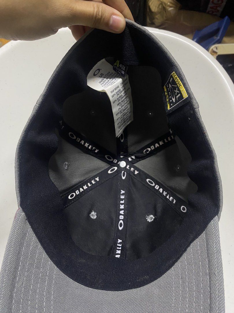 Oakley Classic Low A-Flex Cap Grey L/XL (Category: Caps & Hats) located in Pasacao. Submitted by wengpullar37205 (Listing ID 1466482952, Image 3). Description: - Brand: Oakley - Color: Grey with silver metal ellipse logo on front and black embroidered branding on back - Size: L/XL (A-Flex stretch-fit design) - Material: Comfortable acrylic, wool, and elastane blend - Design: Structured crown, curved brim, and branded interior taping - Condition: 