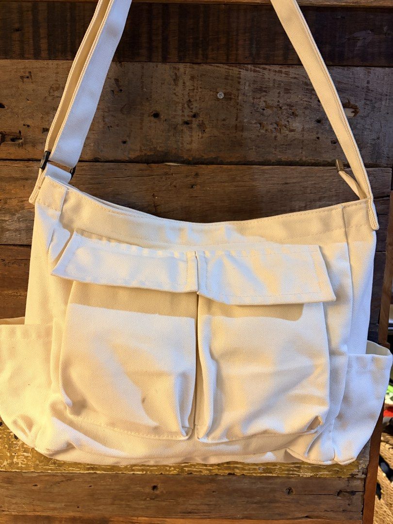 Off-White Canvas Crossbody Bag with Multiple Pockets (Category: Cross-body Bags) located in Quezon City. Submitted by makingroomfinds (Listing ID 1466526532, Image 1). Description: - Color: Off-White (Neutral solid color matches any outfit) - Material: Durable canvas with secure lining - Strap: Adjustable for comfortable wear - Pockets: 2 large front flap pockets, side pockets on both ends, and a back slip pocket - Interior: Includes 1 zippered p