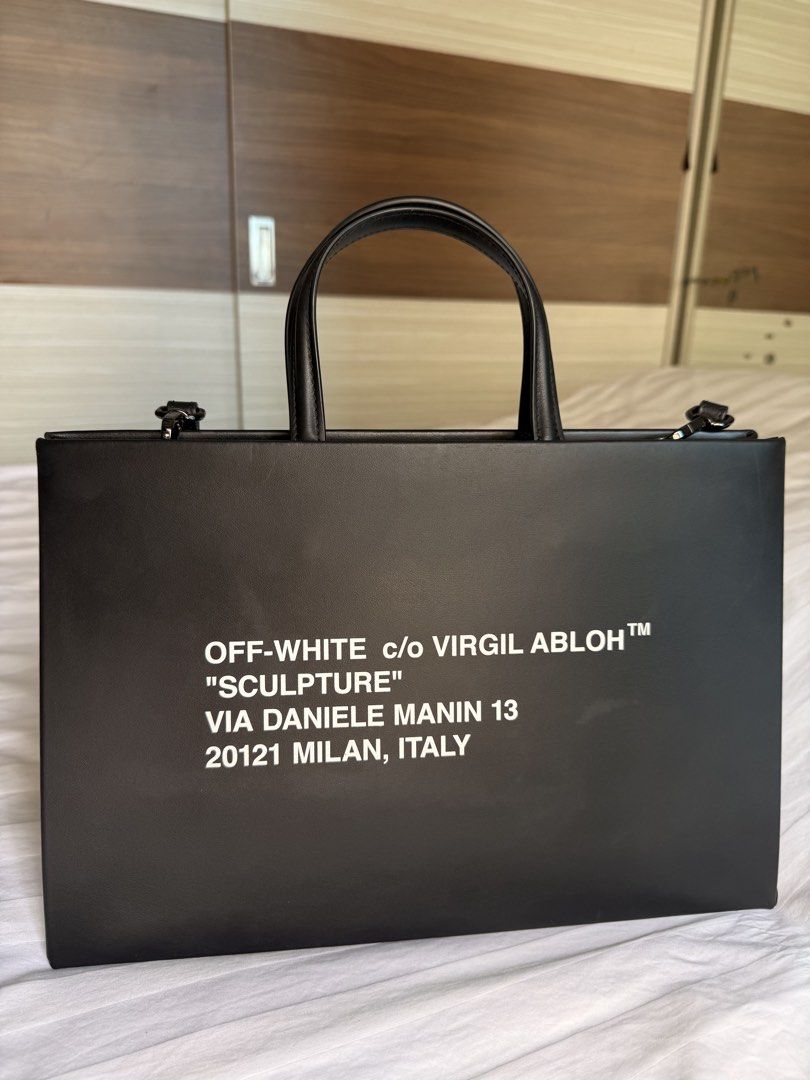 Authentic OFF WHITE Sculpture Leather Tote Bag Black (Category: Tote Bags) located in Taguig. Submitted by _annaq_ (Listing ID 1466376008, Image 3). Description: - Brand: Off-White - Color: Black with iconic white 'Sculpture' lettering on front and arrows graphic on the back - Material: Premium leather with fabric inner lining and interior main label print - Hardware: Heavy-duty hardware with the signature removable yellow industrial strap - Desi