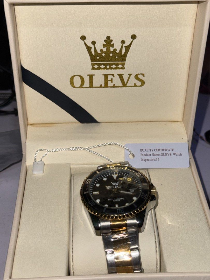 Olevs Dazzling Quartz Watch Gold Silver Two Tone (Category: Women's Watches) located in Paranaque City. Submitted by annann128 (Listing ID 1466560989, Image 1). Description: - Brand: Olevs Quartz Watch - Colorway: Black, Gold, and Silver - Condition: Brand new, unworn, with factory plastics still attached on the bracelet - Features: Rotating bezel and date window at the 3 o'clock position - Strap: Two-tone steel bracelet - Inclusions: Original br
