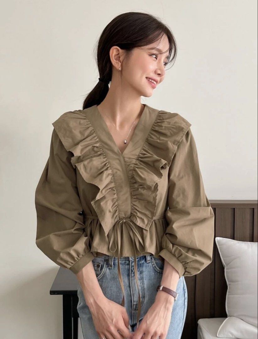 Khaki Ruffle Long Sleeve Blouse Top (Category: Blouses) located in Manila. Submitted by sooprmav (Listing ID 1466548293, Image 2). Description: - Color: Trendy olive green - Design: Dramatic ruffles on neckline and hem, deep V-neck with thin tie strings - Sleeves: Long bishop sleeves with banded cuffs - Fit: Cropped style with gathered waist detail - Condition: Clean fabric, no flaws noticed - Styling: Pairs effortlessly with high-waisted jeans o
