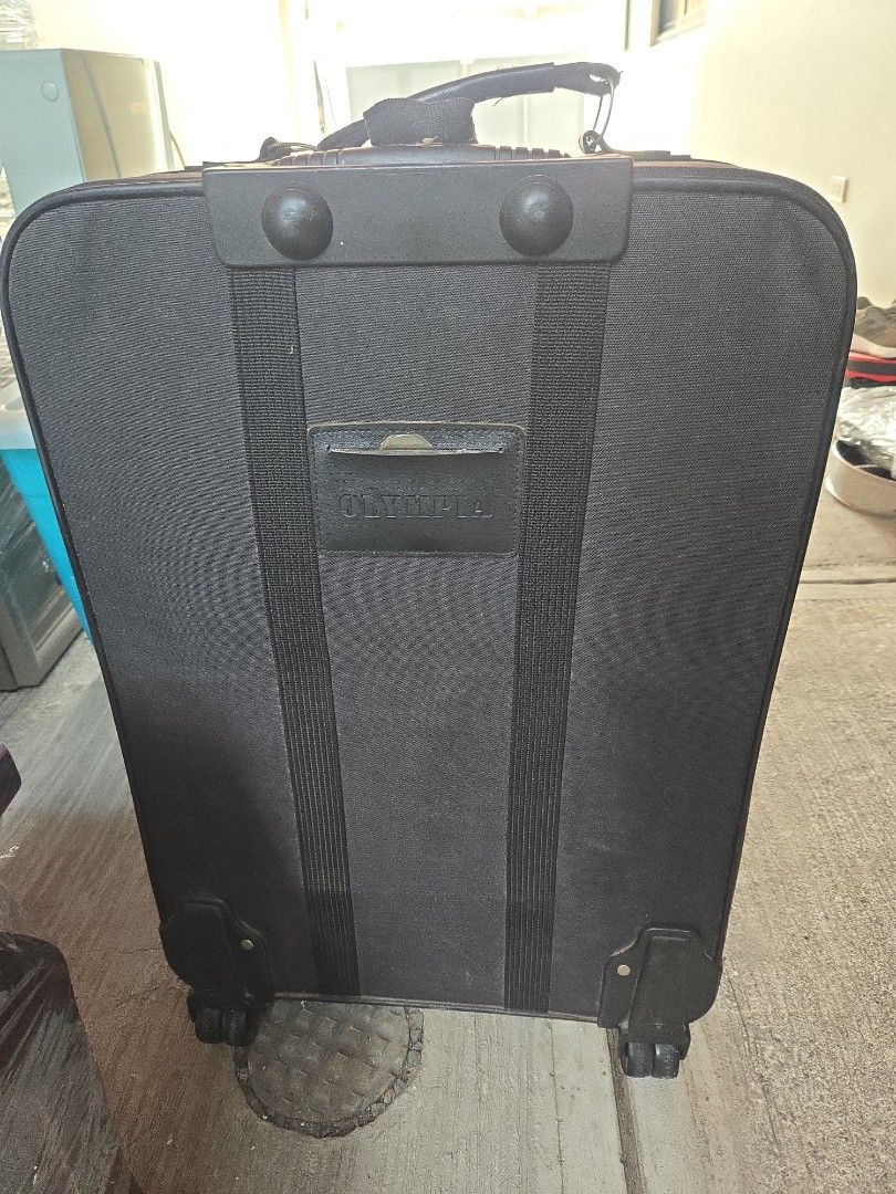 Olympia Black Rolling Suitcase Luggage (Category: Luggage) located in Manila. Submitted by preownedddd (Listing ID 1466344096, Image 3). Description: - Brand: Olympia - Color: Classic black fabric - Mobility: Smooth rolling wheels with a retractable handle - Storage: Multiple exterior zippered pockets for easy access - Durability: Sturdy reinforced corner guards and horizontal support straps - Condition: Clean exterior with minor signs of handlin