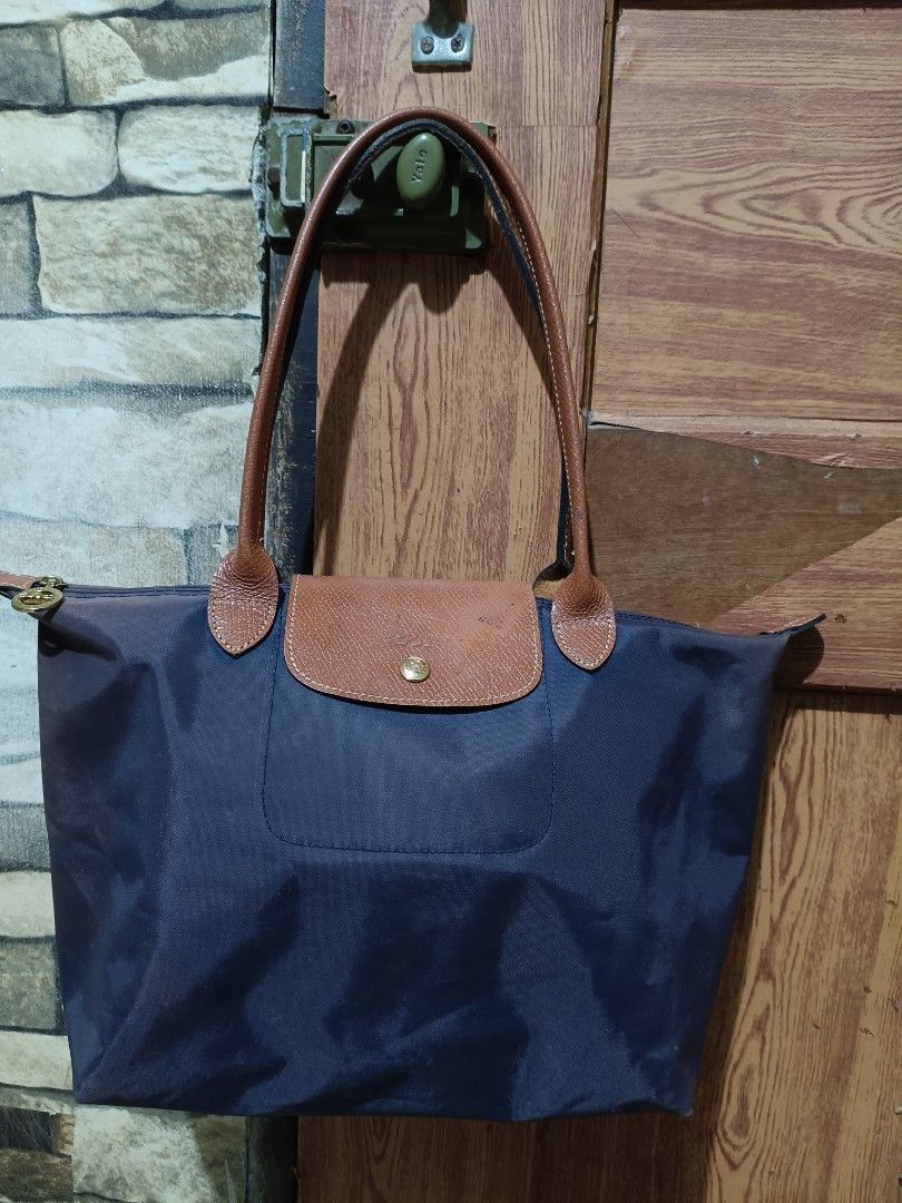 Original Longchamp Le Pliage Navy Blue Tote Bag (Category: Luxury Bags & Wallets) located in Manila. Submitted by rsnnpr24 (Listing ID 1466468284, Image 1). Description: - Authentic Longchamp Le Pliage shoulder bag (Made in France) - Color: Navy blue with brown leather handles and flap - Material: Durable foldable nylon body with gold-tone hardware - Closure: Zip top with iconic jockey medallion pull and snap button - Model details: Interior tag 