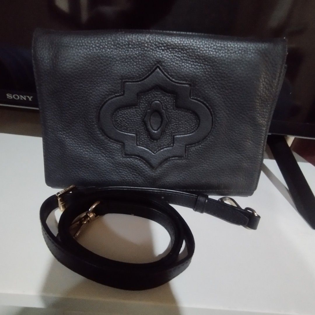 OryanyBlack Leather Crossbody Bag (Category: Cross-body Bags) located in Manila. Submitted by lene48 (Listing ID 1466445396, Image 2). Description: Black textured leather crossbody bag. Front has a distinct debossed geometric medallion design. Top zipper closure with a matching wrist strap on the side. Includes an adjustable, detachable shoulder strap. Inside lining has a printed geometric pattern . Clean interior with a zip pocket..