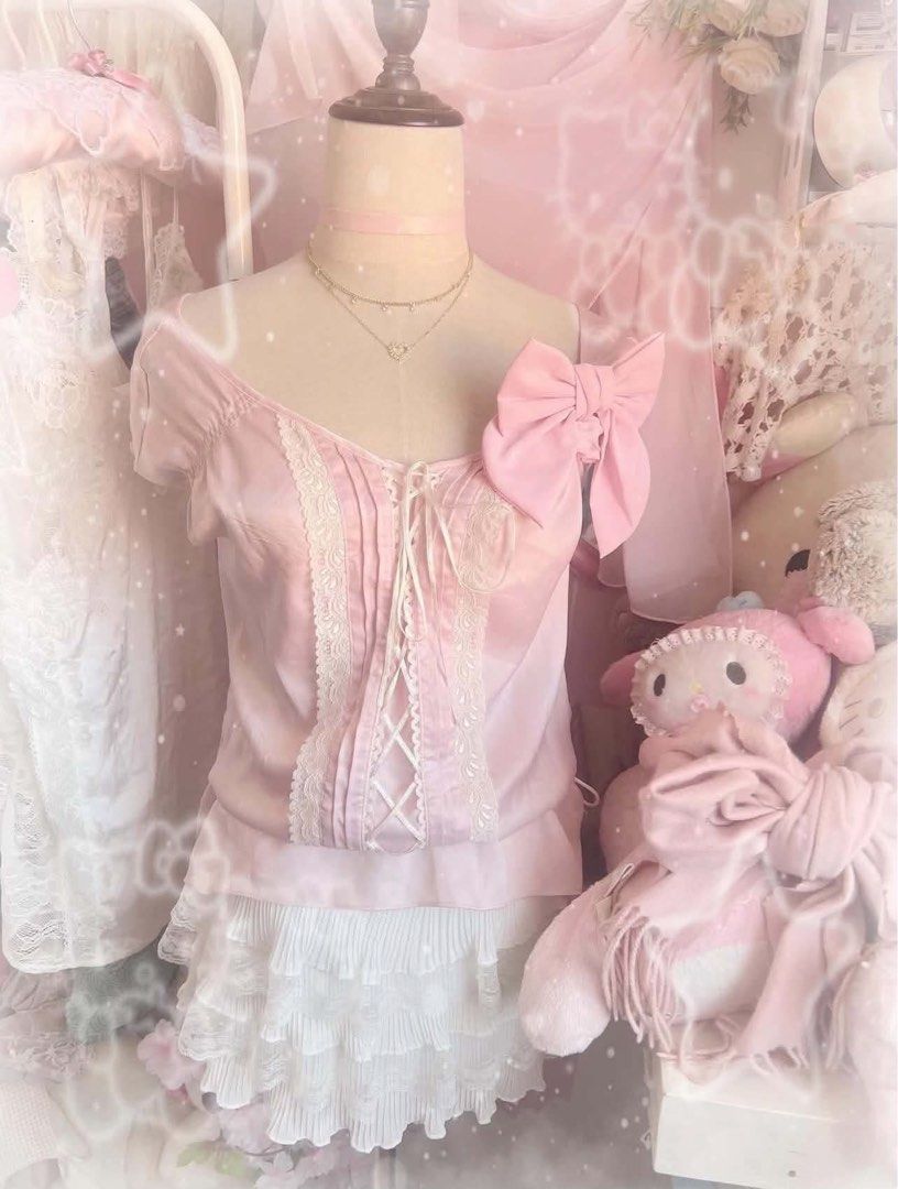 pink baby doll top (Category: Blouses) located in Minalin. Submitted by peelmyoranges (Listing ID 1466490906, Image 1). Description: Light pink off-shoulder top with short puff sleeves. Front features delicate cream lace trim, pleating, and lace-up ribbon ties. Large pink side bow pinned near the shoulder. Paired with a layered white pleated ruffle mini skirt. Soft pastel coordinate, sweet doll vibe..