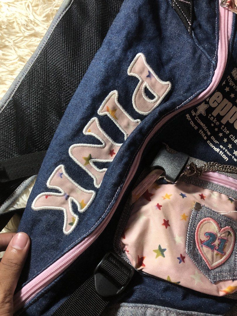 Pink Cross Body Bag Y2k (Category: Cross-body Bags) located in Maria Aurora. Submitted by kylerikathriftshop101010 (Listing ID 1466513704, Image 2). Description: no issues - Style: Vintage street style denim sling backpack with grey and pastel pink accents - Design: Pink star pattern, large embroidered 'pink' text, and 'Steppers' graphics on the front - Storage: Small front pouch with a mini heart pocket, '21' patch, and attached chain detail - C