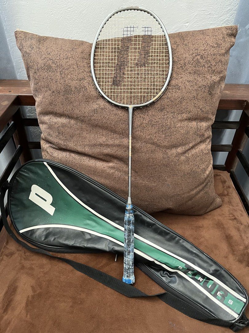 Prince Badminton Racket with Cover Case (Category: Racket and Ball Sports) located in Antipolo. Submitted by jccruise (Listing ID 1466348568, Image 1). Description: - Brand: Prince badminton racket - Color/Design: Metallic silver frame with strung net - Accessories: Includes matching green and black cover bag with adjustable strap - Condition Note: Blue grip tape has heavy wear and peeling - Ideal For: Casual games and backyard matches.