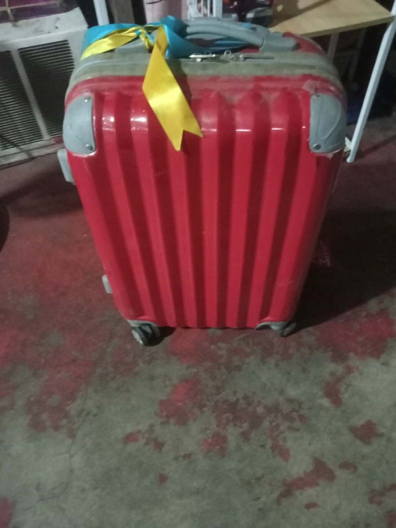 Red Hardshell Luggage Suitcase With Wheels And Ribbon (Category: Luggage) located in Quezon City. Submitted by madelrivera (Listing ID 1466445205, Image 1). Description: - Color & Design: Bright red hardshell with textured vertical stripes and blue/yellow ribbon on the handle - Mobility: 4 smooth-rolling spinner wheels - Features: Grey reinforced corners, sturdy top handle, and secure top zip closure - Condition: Good functional condition with mi