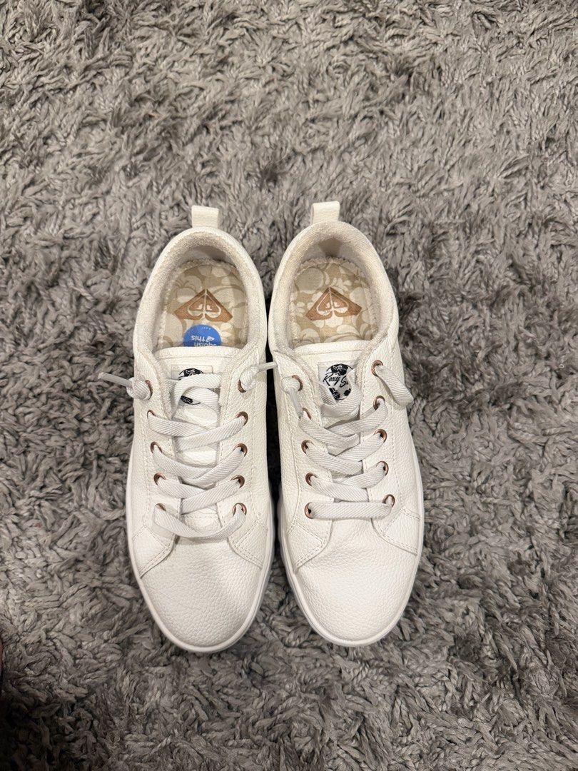 Roxy White Casual Sneakers (Category: Sneakers) located in Pasig City. Submitted by CuratedProj (Listing ID 1466473238, Image 2). Description: - Brand: Roxy - Color: White with rose gold accents - Material: Leather-look finish - Details: Rose gold eyelets, floral printed insoles with Roxy heart logo, and 'squish this' cushioned insoles for extra comfort - Features: Convenient back heel pull tabs and clean white outsoles - Style: Versatile slip-on