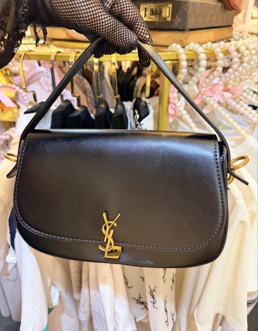Saint Laurent YSL Black Leather Shoulder Bag (Category: Luxury Bags & Wallets) located in Dumaguete. Submitted by lovebags.ph (Listing ID 1466394744, Image 1). Description: - Brand: Saint Laurent - Material: Premium smooth leather in classic black - Hardware: Signature gold-tone YSL monogram and side attachments - Design: Structured rectangular shape with rounded bottom corners and tonal stitching - Features: Matching top handle and optional stra