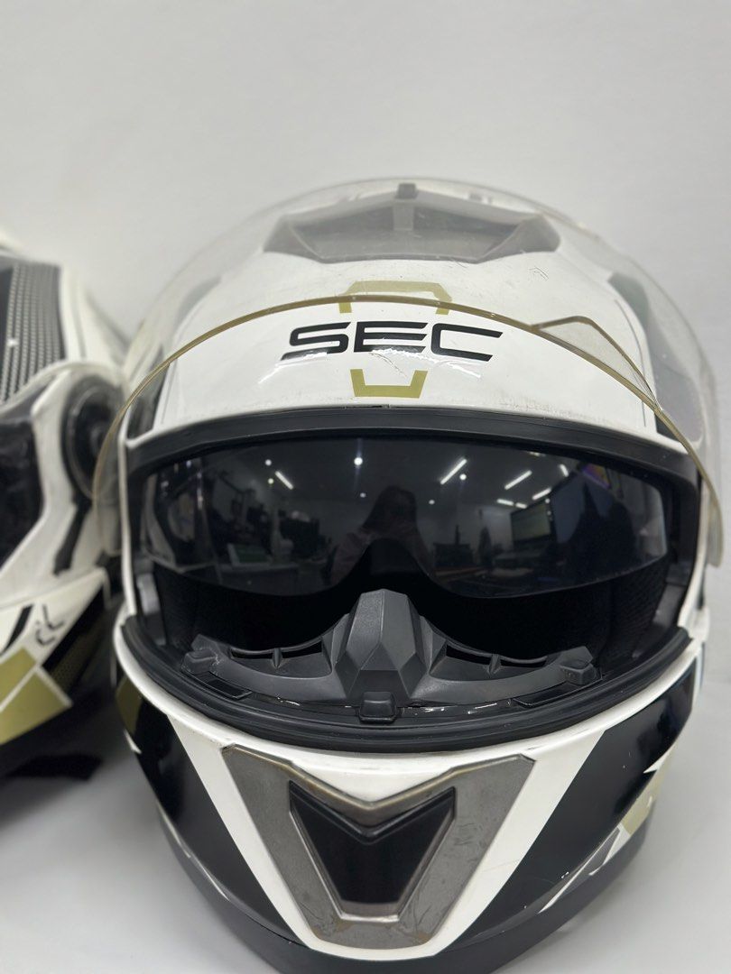 SEC Motorcycle Helmet - Phantom Race (Category: Bicycles) located in Manila. Submitted by cnmanaois19234 (Listing ID 1466563038, Image 3). Description: - Brand: SEC Motorcycle Helmet - Color/Design: White, black, and gold graphics - Type: Full face coverage with clear visor and retractable inner sun shield - Comfort & Fit: Clean, intact interior padding with adjustable strap and quick-release buckle - Ventilation: Top and front ventilation vents 