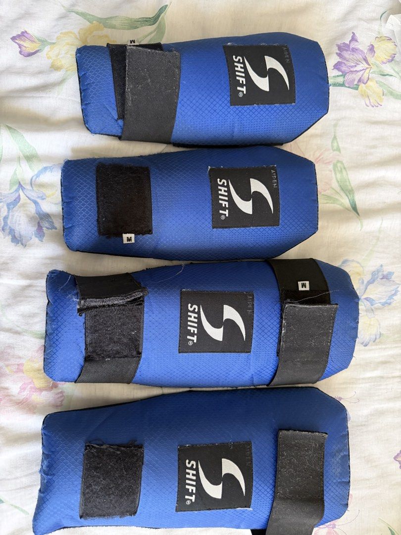 Shift Blue Size M Protective Guards (Category: Combat Sports) located in Manila. Submitted by fitandshop (Listing ID 1466515748, Image 1). Description: - Brand: Shift - Quantity: Set of four guards - Size: Medium - Material/Design: Blue honeycomb textured fabric with black mesh backing - Closure: Secure black Velcro straps - Branding: Clear white logo patch on the front - Condition/Use: Ideal for sports and training Flaws: need to change strap .