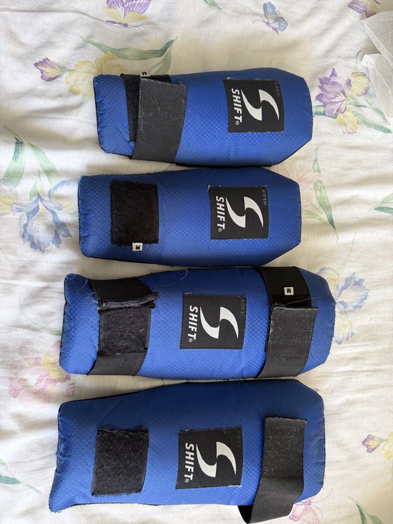 Shift Blue Size M Protective Guards (Category: Combat Sports) located in Manila. Submitted by fitandshop (Listing ID 1466515748, Image 2). Description: - Brand: Shift - Quantity: Set of four guards - Size: Medium - Material/Design: Blue honeycomb textured fabric with black mesh backing - Closure: Secure black Velcro straps - Branding: Clear white logo patch on the front - Condition/Use: Ideal for sports and training Flaws: need to change strap .