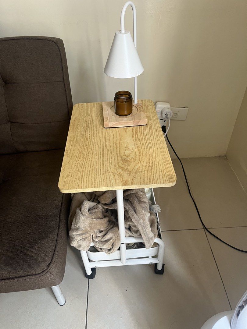 Side table (Category: Shelves, Cabinets & Racks) located in Manila. Submitted by kyleoliveros (Listing ID 1466359082, Image 2). Description: - Mobile bedside table with smooth-rolling wheels - Stylish wooden top paired with a sturdy white metal frame - Convenient lower storage basket for books and small items - Compact size, ideal for small spaces beside a bed or sofa - Previously used in a clean bedroom setting and well-maintained RFS: Planning 