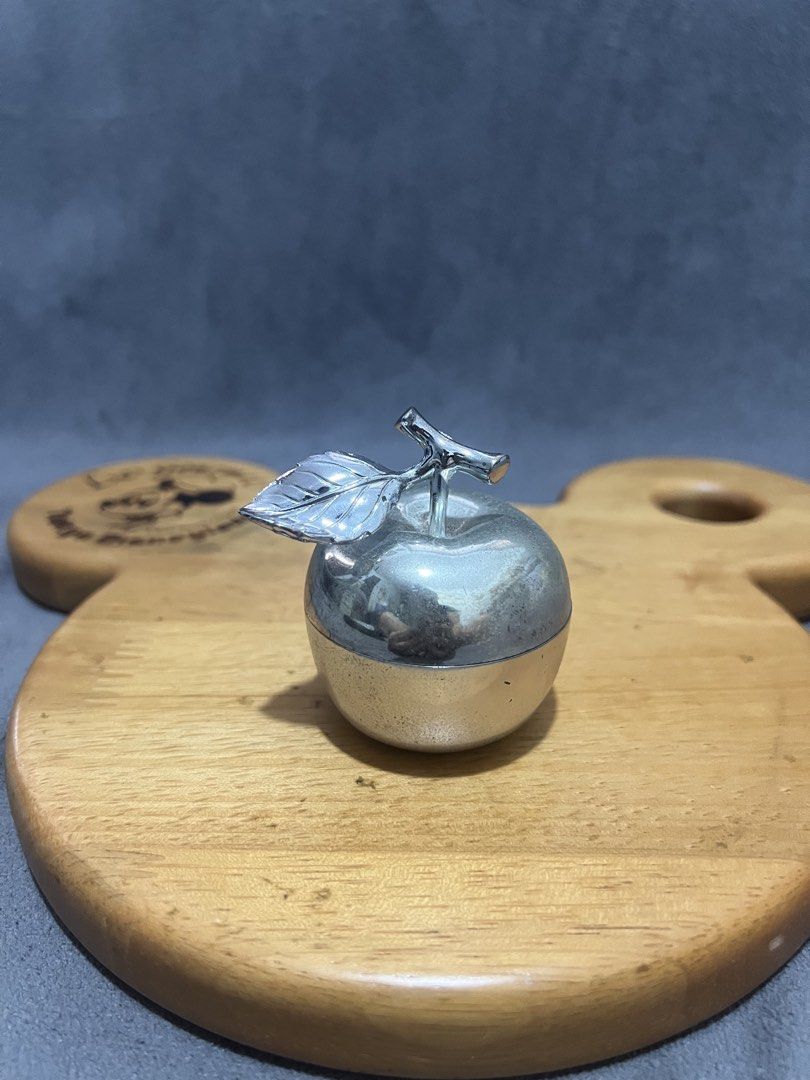 Silver Apple Shaped Trinket Box with Lid (Category: Accessory Holder, Box & Organizers) located in Las Pinas. Submitted by maple0305 (Listing ID 1466413520, Image 1). Description: Silver-toned metal apple trinket box with a stem and leaf handle. Inner bowl is white ceramic or enamel. Cute little container for small jewelry, pills, or desk bits. Lid fits right on top with a small cutout for a spoon or just easy lifting. Polished silver finish with
