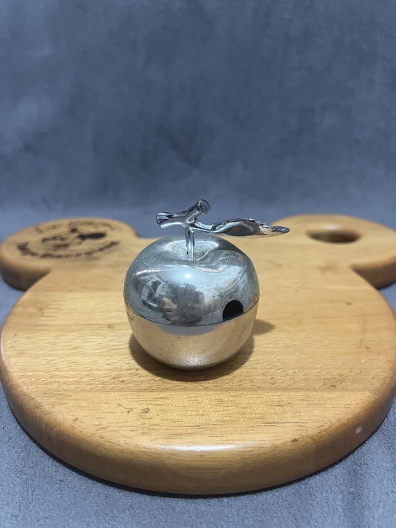 Silver Apple Shaped Trinket Box with Lid (Category: Accessory Holder, Box & Organizers) located in Las Pinas. Submitted by maple0305 (Listing ID 1466413520, Image 2). Description: Silver-toned metal apple trinket box with a stem and leaf handle. Inner bowl is white ceramic or enamel. Cute little container for small jewelry, pills, or desk bits. Lid fits right on top with a small cutout for a spoon or just easy lifting. Polished silver finish with