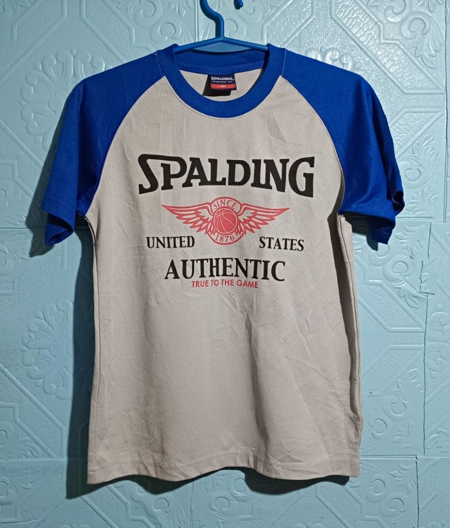SPALDING AUTHENTIC ACTIVE WEAR (Category: Activewear) located in Quezon City. Submitted by zoesmithshop (Listing ID 1466478498, Image 1). Description: SPALDING authentic T-shirt Size- Small No issue good condition Color -Blue & grey This retro Spalding raglan tee features bold royal blue sleeves and a classic winged 1876 basketball graphic.