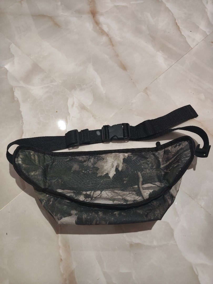 Supreme Camo Waist Bag (Category: Belt bags, Clutches and Pouches) located in Rizal, Mindoro Occidental. Submitted by finding_ukaygems5103 (Listing ID 1466509323, Image 3). Description: - Brand: Supreme - Style: Tree camouflage waist bag - Details: Large white Supreme lettering and iconic red box logo patch - Storage: Top zipper closure, ideal for phone, keys, and wallet - Fit: Adjustable black strap with durable plastic buckle - Condition: Good 