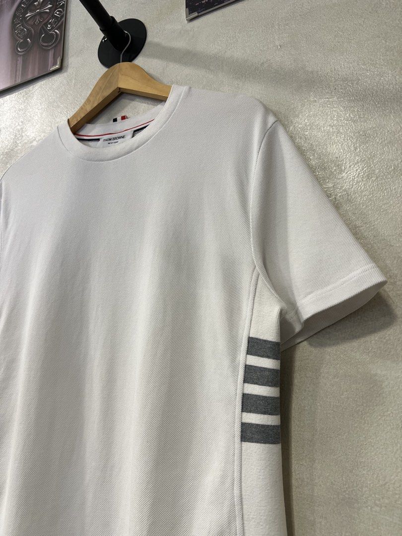Thom Browne Classic Pique 4-Bar Tee (Category: Formal Shirts) located in Manila. Submitted by -handpick- (Listing ID 1466372640, Image 2). Description: Thom Browne Classic Pique 4-Bar Tee Features a crew neckline, signature grey 4-Bar stripes on the left side, and a signature tricolor grosgrain loop tab at the back neck. Size : 0 Dimensions : Length : 27 inches Width : 20 inches Shoulder : 18.5 inches Sleeve : 9.5 inches Sign of wear in good cond