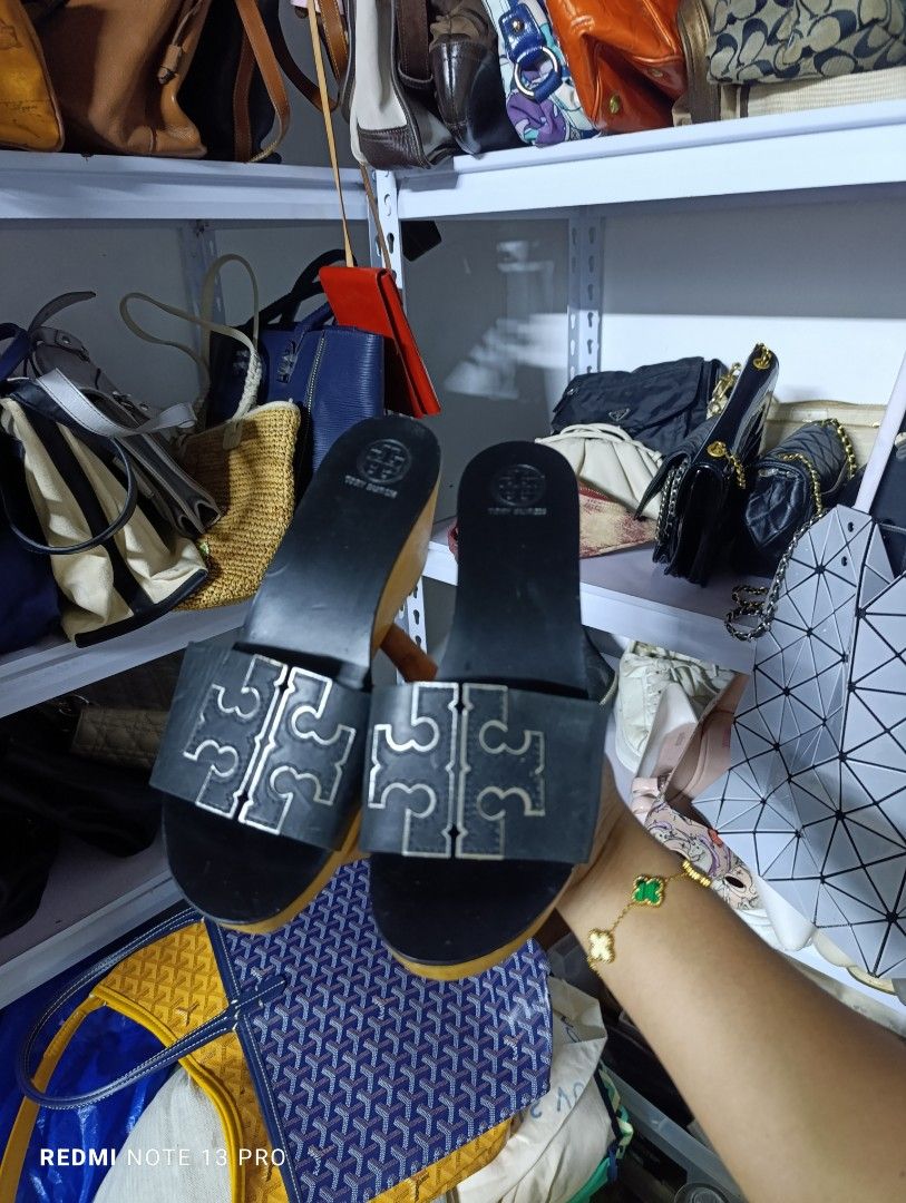 Tory Burch Black Wedge Sandals Size US 8 (Category: Wedges) located in Naguilian. Submitted by jhoyukay (Listing ID 1466405392, Image 1). Description: - Brand: Tory Burch - Style: Slip-on open-toe wedge sandals - Color: Classic black with wooden heels and silver-tone hardware - Detail: Oversized silver metal logo on the front strap - Condition: Excellent, minimal wear on the soles - Perfect for daily wear, smart-casual outfits, and effortless sty
