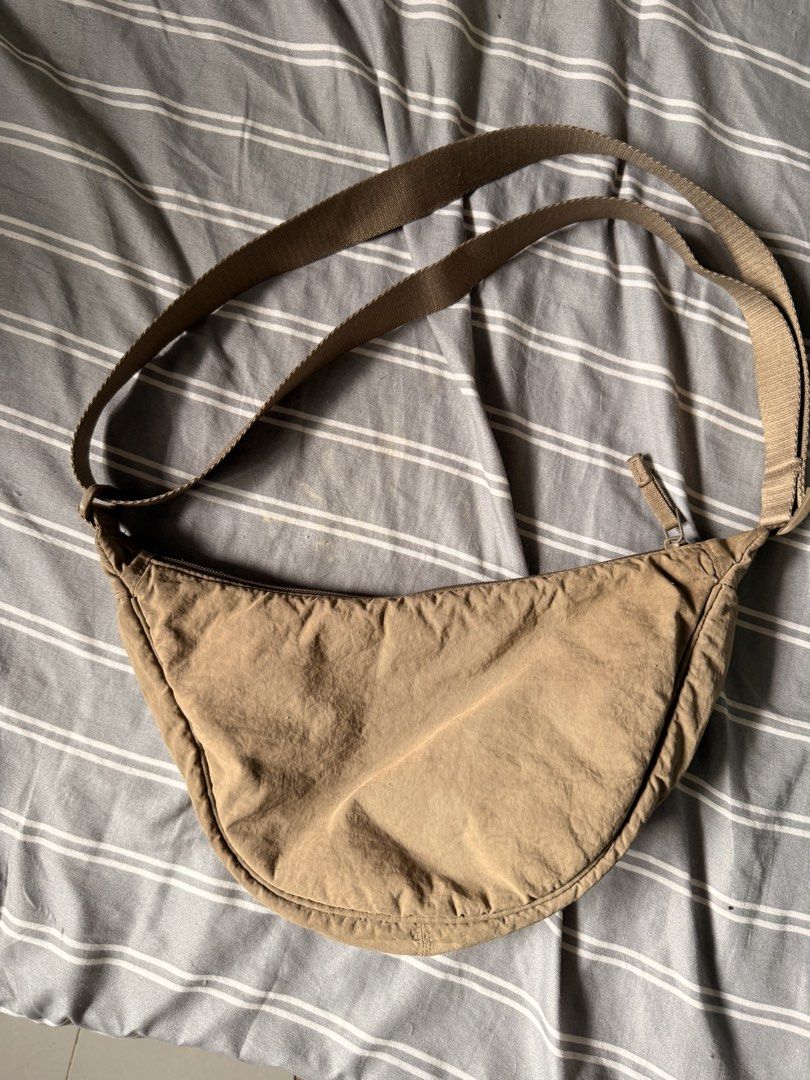 Uniqlo Round Mini Shoulder Bag Brown (Category: Cross-body Bags) located in Mandaluyong City. Submitted by ohayouclub (Listing ID 1466362174, Image 2). Description: - Brand: Uniqlo - Style: Round Mini Shoulder Bag (Crescent shape) - Color: Versatile beige brown - Material: Durable and lightweight nylon - Closure: Secure zipper with interior pockets for organization - Strap: Adjustable for a comfortable fit.