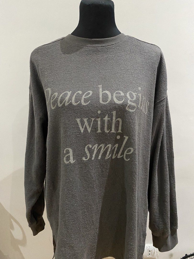 Waffle Knit Long Sleeve Sweater Grey (Category: Longsleeves) located in Manila. Submitted by mpt99876 (Listing ID 1466516240, Image 1). Description: - Brand: Samansa Mos2 - Color: Versatile Grey - Material: Soft textured waffle knit fabric - Fit: Relaxed fit with long sleeves and ribbed crew neckline - Design: 'peace begins with a smile' letter print in a slightly metallic font - Special Detail: Contrasting woven fabric panel on the upper back - 