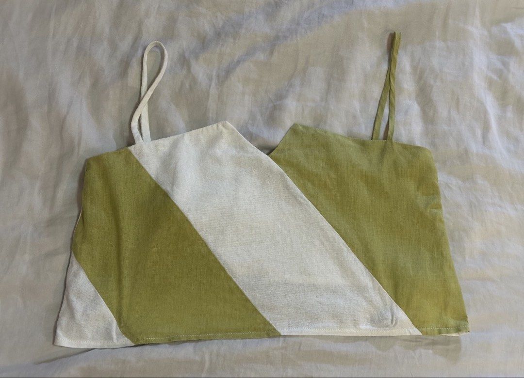 Wear Anika Indy Green Top (Category: Sleeveless) located in Pasig City. Submitted by kutleyn (Listing ID 1466408433, Image 2). Description: - Color: Green and white color-blocked - Material: Breathable linen, great for hot weather - Design: Asymmetrical geometric stripes with thin spaghetti straps and cropped length - Styling: Pairs perfectly with high-waisted skirts and pants - Condition: Worn once, washed and clean, no stains or loose threads.