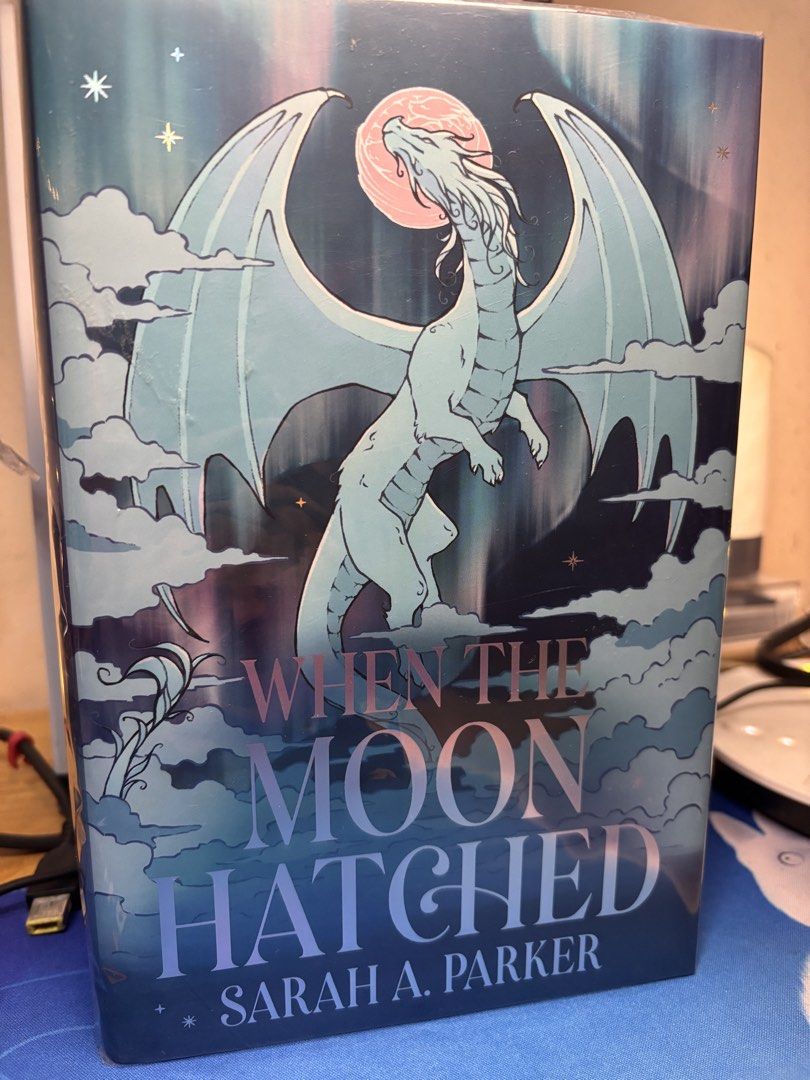 When The Moon Hatched (Signed FairyLoot) (Category: Storybooks) located in Quezon City. Submitted by ryuji35 (Listing ID 1466551156, Image 1). Description: - Title & Author: When The Moon Hatched by Sarah A. Parker - Format: Hardcover fantasy novel - Cover Design: Stunning white dragon against a dark blue background with a pink moon, clouds, and shiny foil lettering - Condition: Brand new, plastic wrapped over Dust Jacket - Storage: Carefully sto