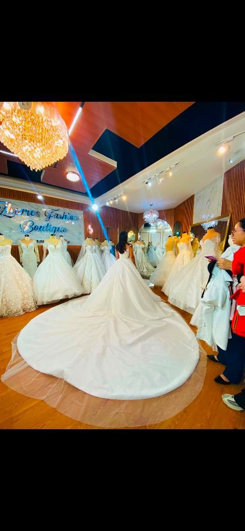 White lace wedding gown with long train (Category: Evening dresses & gowns) located in Caloocan City. Submitted by rhianskie (Listing ID 1466374918, Image 3). Description: - Condition: Worn only during my wedding - Style: sleeveless bodice with intricate lace detailing - Skirt: Full, voluminous ballgown skirt layered in tulle - Back Design: Deep V-back with a delicate row of buttons - Train: Dramatic floor-sweeping train with a sheer outer tulle 