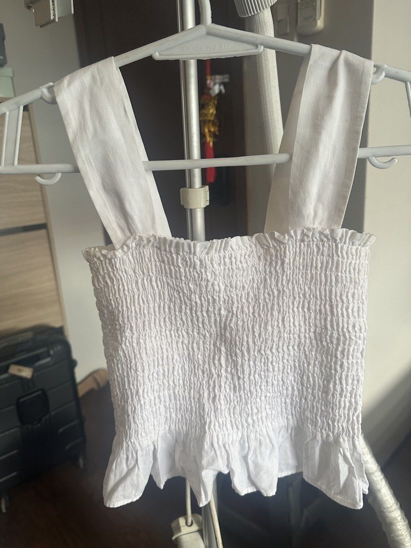 White smocked crop top with thick straps (Category: Sleeveless) located in Makati City. Submitted by alyssa1718 (Listing ID 1466393642, Image 1). Description: - Colour: Clean bright white - Style: Sleeveless crop top with wide shoulder straps - Material: Stretchy, lightweight smocked fabric - Details: Cute ruffled hem at the bottom - Versatility: Easy to pair with high-waisted jeans or skirts, great for travel and warm weather.