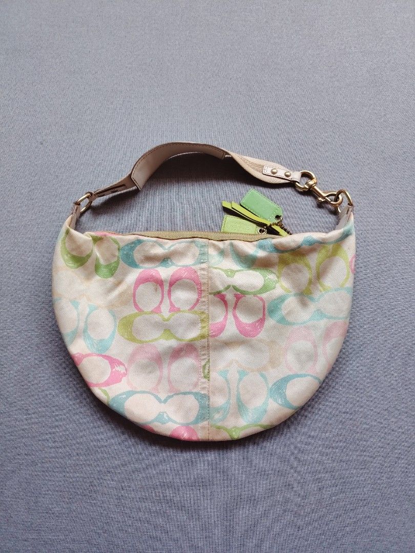 WTS !! Y2K Coach Scribble Pastel Monogram Hampton Hobo Shoulder Bag / Handbag (Category: Luxury Bags & Wallets) located in Taguig. Submitted by _theroom.ph (Listing ID 1466375607, Image 3). Description: Coach hobo bag with multi-color signature C graffiti print in pink, blue, and green. Off-white canvas body with light green trim and neon green leather hangtags. Single adjustable shoulder strap with gold-tone hardware. Front slip pocket with snap