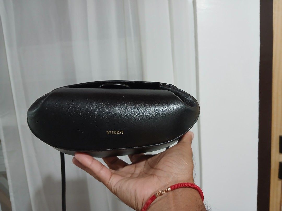 Yuzefi Black Leather Shoulder Bag (Category: Shoulder Bags) located in Quezon City. Submitted by mcenon35 (Listing ID 1466480023, Image 3). Description: - Brand: Yuzefi - Material: Premium black leather with gold-tone hardware - Design: Structured compact bag with gold logo stamped on the front flap - Strap: Thin black strap featuring stylish knot details on the sides - Condition: Clean, well-maintained overall - Capacity: Ideal size for your dai
