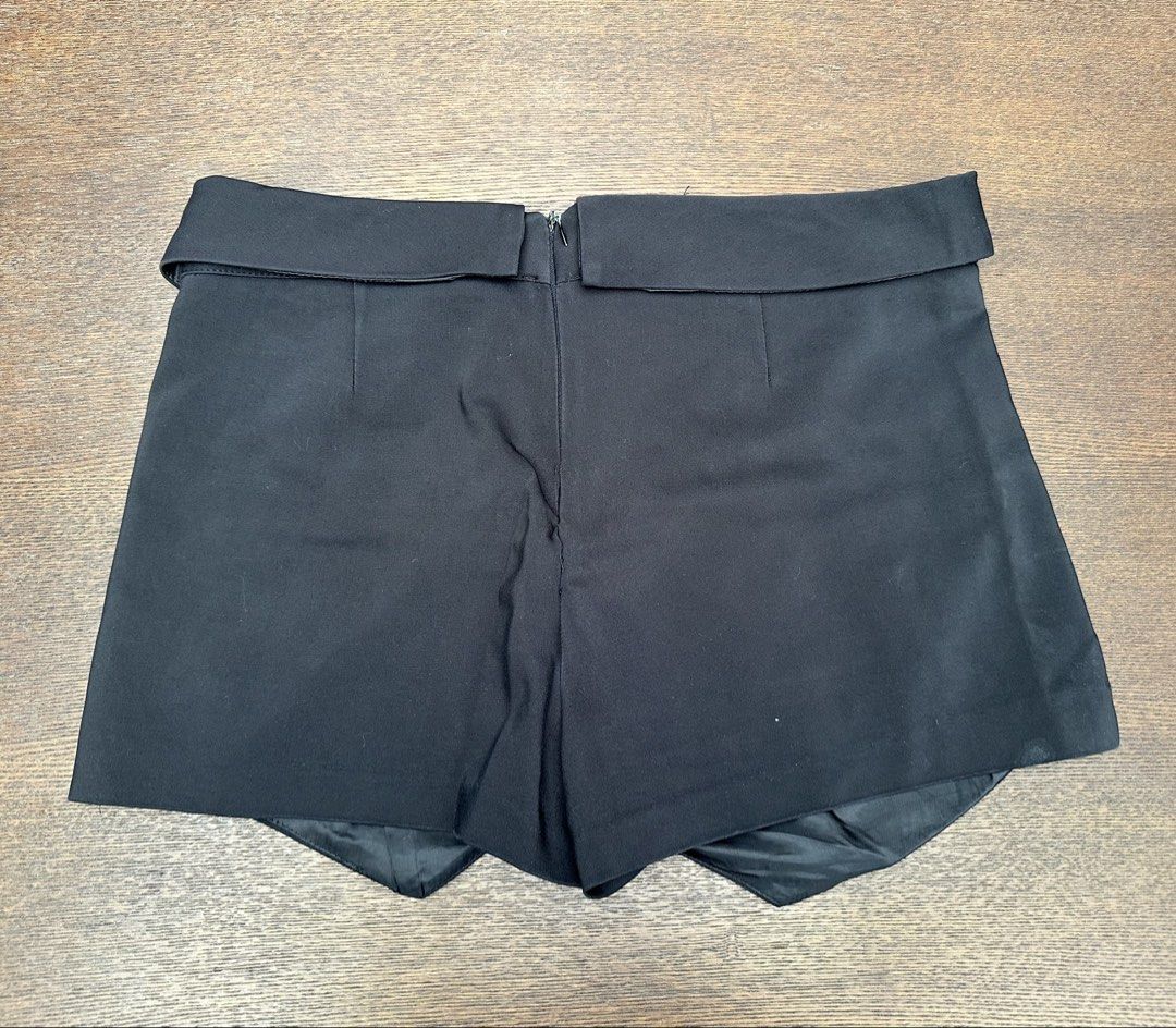 Zara Black Skort (Category: Skirts) located in Bulacan. Submitted by thriftbagcollections (Listing ID 1466356591, Image 2). Description: - Brand: Zara Basic - Size: S / 26 - Made in Turkey - Color: Solid black (versatile for any outfit) - Design: Asymmetric wrap-around front panel - Closure: Hidden back zipper - Comfort: Soft fabric interior lining - Condition: Excellent.