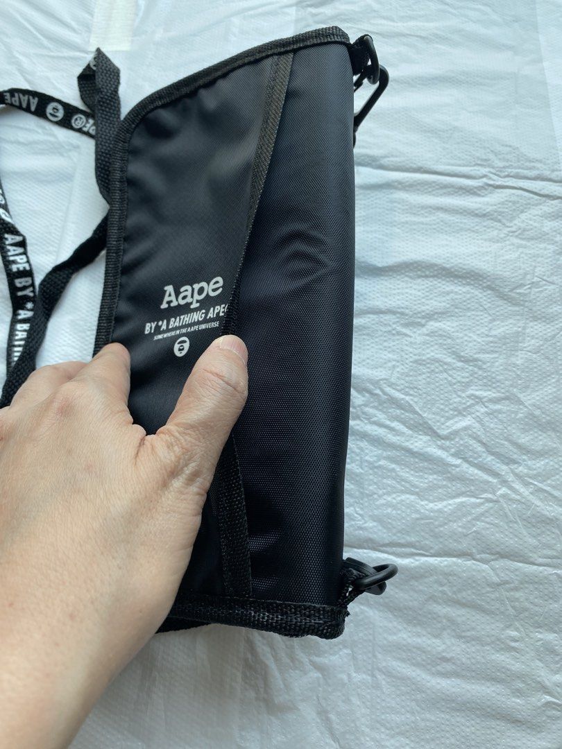 AAPE BY A BATHING APE 黑色頸繩銀包 （分類：手袋及銀包）位於 Hong Kong。 由 hellomami 提交（商品編號 1466591026，圖片 3）。簡介： AAPE 黑色長銀包，有品牌經典猿人頭 Logo 同埋字母印花。附送同款字樣黑色掛頸繩，方便出街掛頸或者斜孭。入面有多個卡位同隔層，放到好多卡同現金，拉鍊開合好安全。尺寸大約 21cm 長，實用又易襯。 型人必選系列，出街、去旅行都啱用。