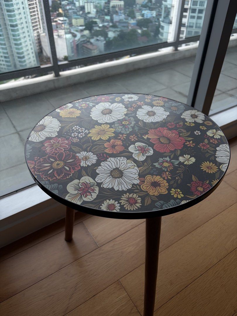 Accent Side Table with Wooden Legs (Category: Tables & Sets) located in Mandaluyong City. Submitted by vickydeclutter (Listing ID 1466640180, Image 1). Description: I was using it for my portrait display and some candles. This is decorative table only Price negotiable - Type: Round side table - Design: Dark floral print with vibrant white, yellow, and red flowers - Build: Sturdy tabletop with smooth edges and three screw-in wooden legs with secur
