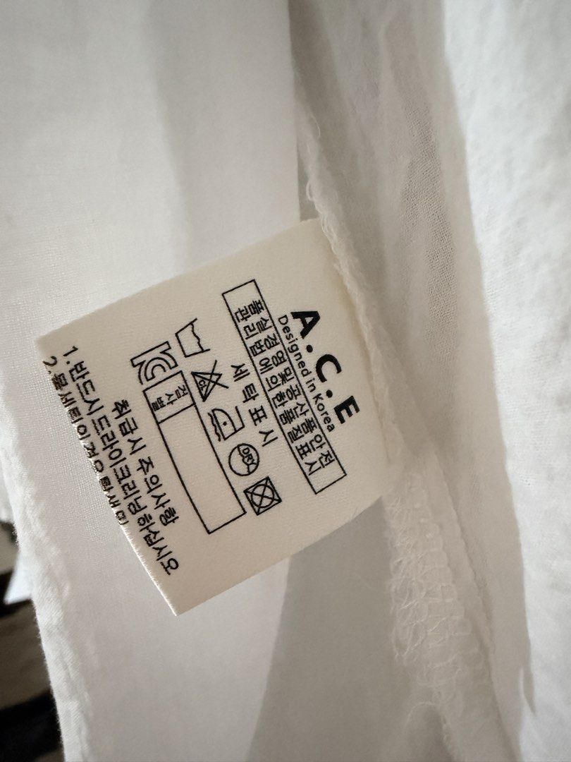 A.C.E. Designed in Korea White Button-Up Shirt (Category: Shirts) located in Taguig. Submitted by mengxir20193848 (Listing ID 1466673040, Image 2). Description: - Brand: A.C.E. (Designed in Korea) - Color: Classic White - Style: Korean streetwear, versatile neutral staple - Fit/Material: Lightweight, slightly sheer, long sleeves with classic collar and front button closure - Versatility: Easy to wear solo or layer over a tank top.