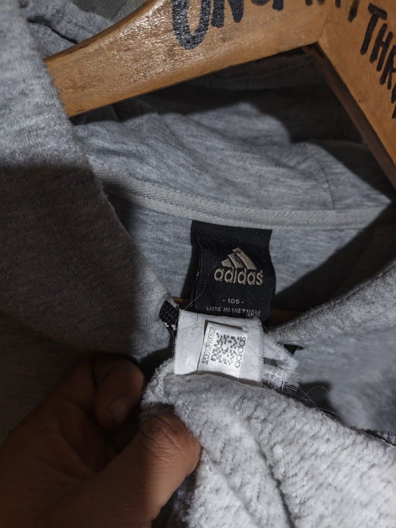 Adidas Grey Hoodie Size 105 (Category: Hoodies) located in Maasim. Submitted by ukayganda25 (Listing ID 1466707569, Image 2). Description: - Authentic grey Adidas hoodie with official branding - Large black logo printed across the chest - Small Adidas logo on the left sleeve cuff - Equipped with a drawstring hood and front kangaroo pocket - Size: 105 (Made in Vietnam) - Condition: Excellent, great for everyday casual style.